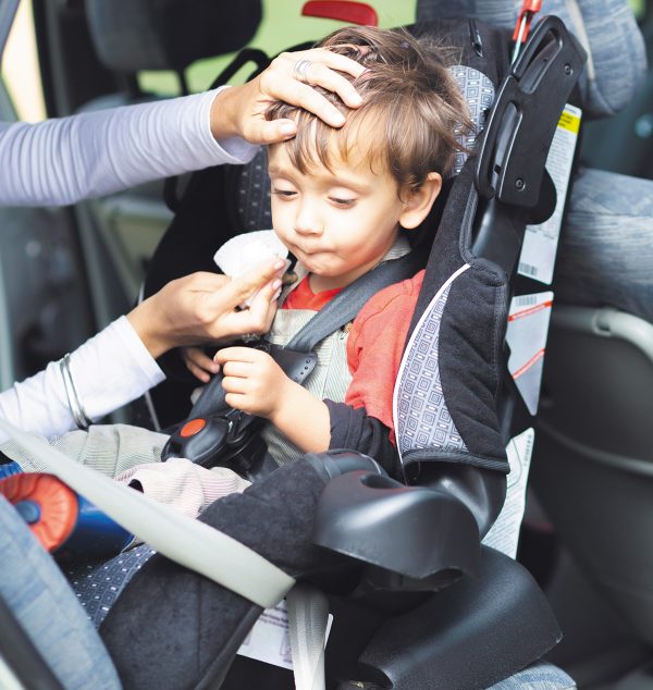 Happy Mother helping her son to fasten, seatbelts in the car